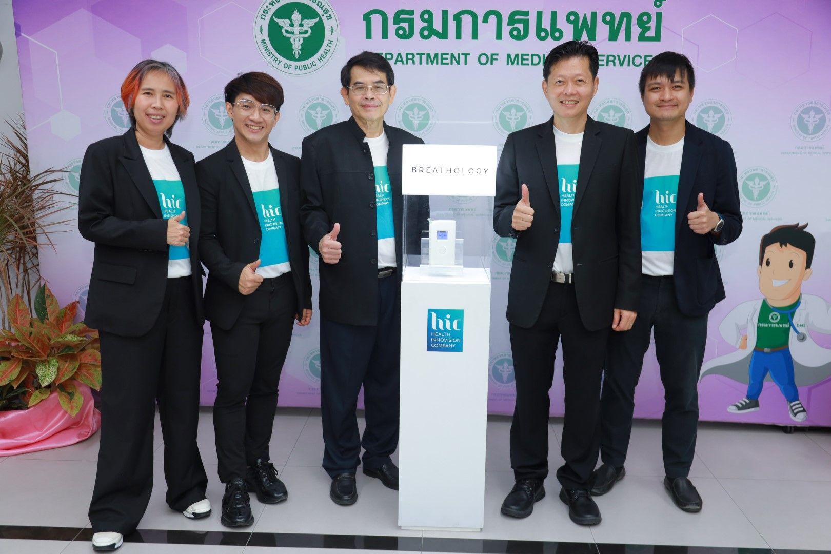 A group of people are standing next to each other and giving a thumbs up.