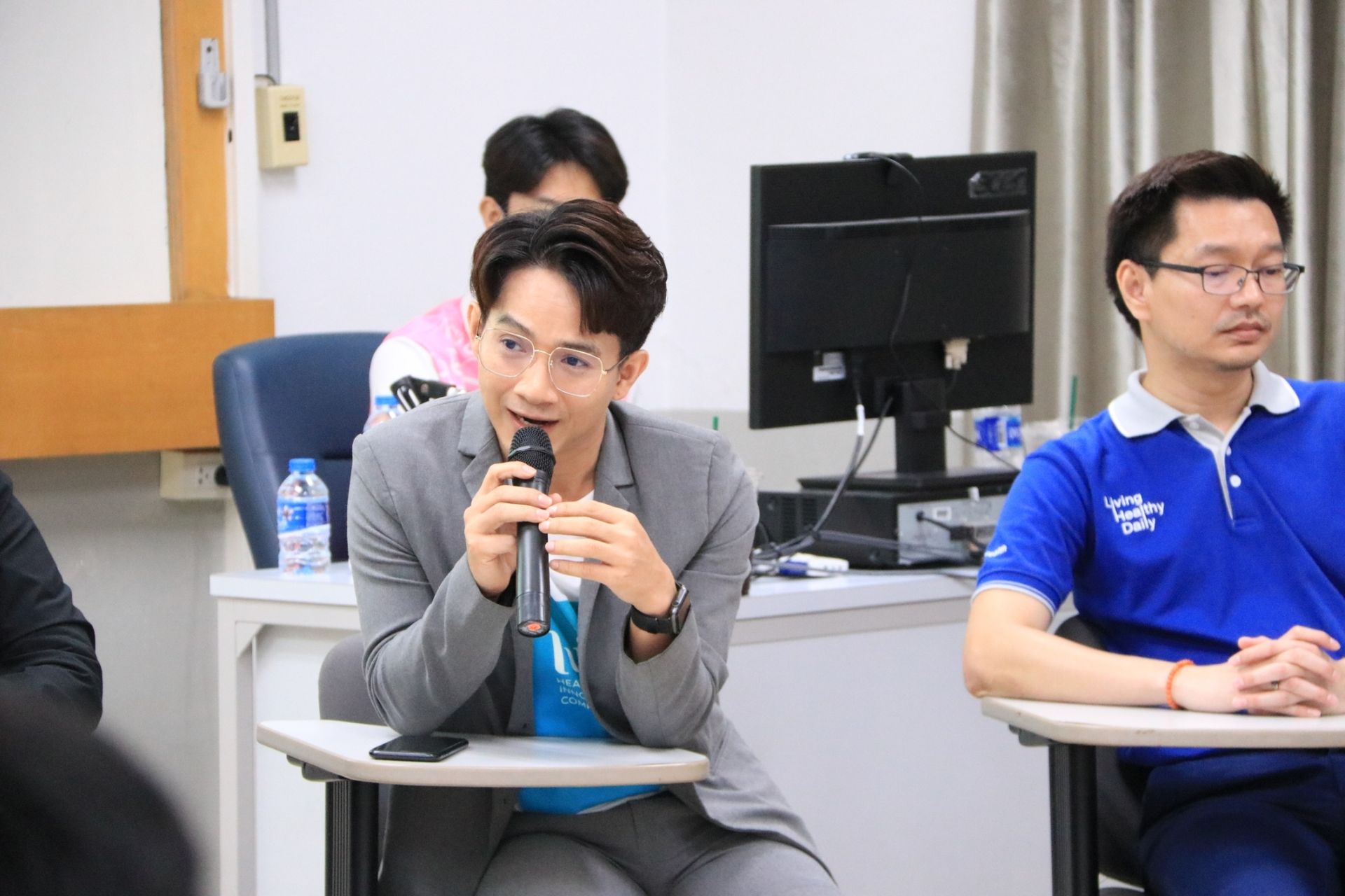 A woman is sitting at a desk holding a microphone.