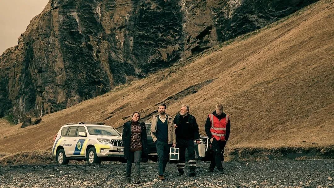 Fimm manns við hlið hvíts bíls á grýttri hlíð, klæddir útivistarfatnaði.