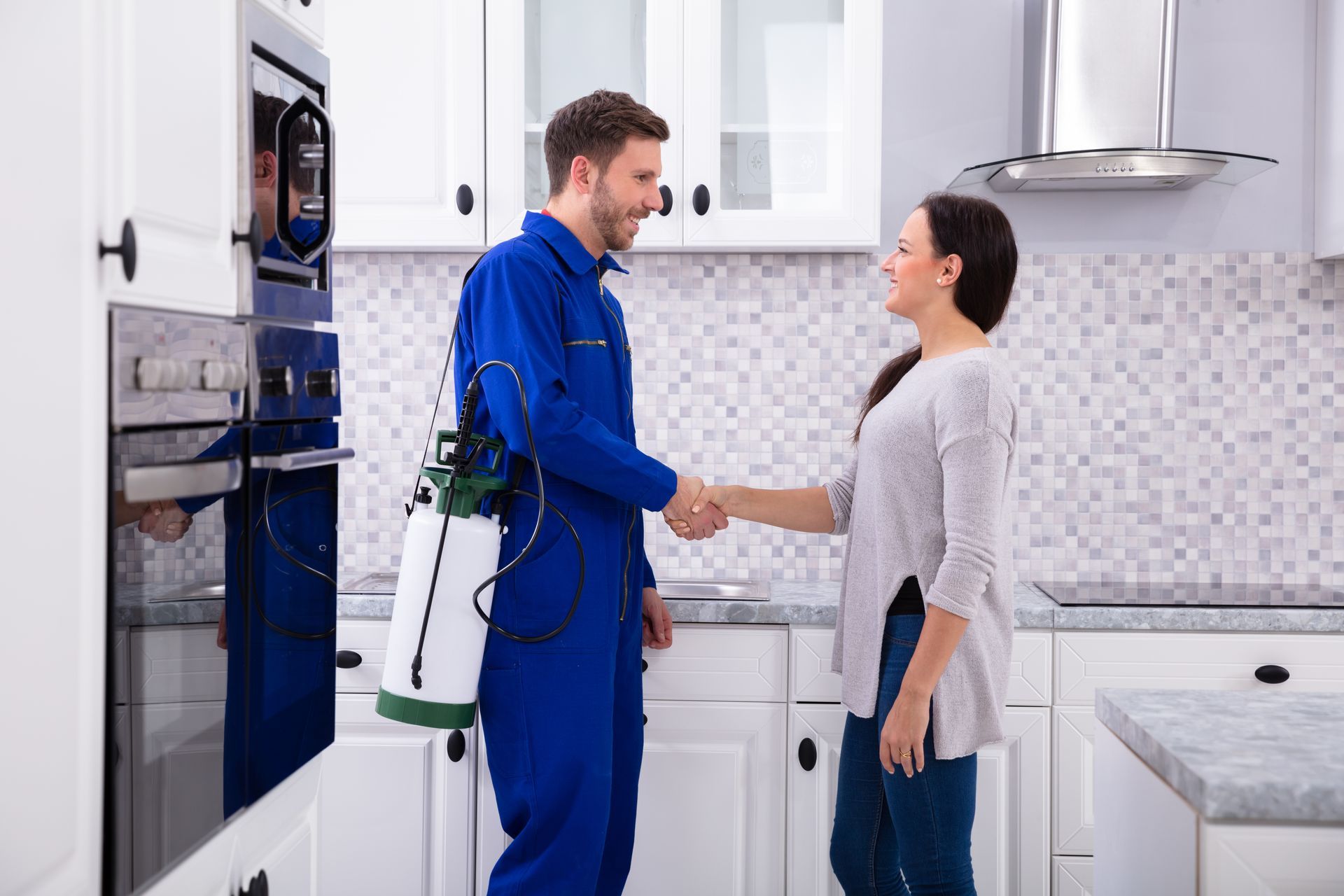 A pest control worker is shaking hands with a woman.