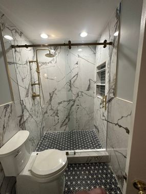 A bathroom with a toilet , shower , and mirror.