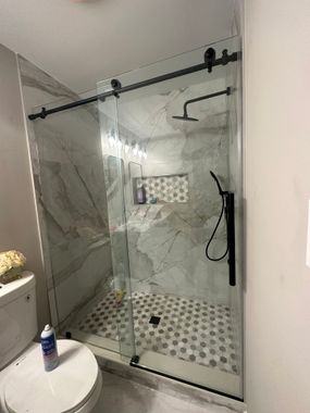 A bathroom with a sliding glass shower door and a toilet.
