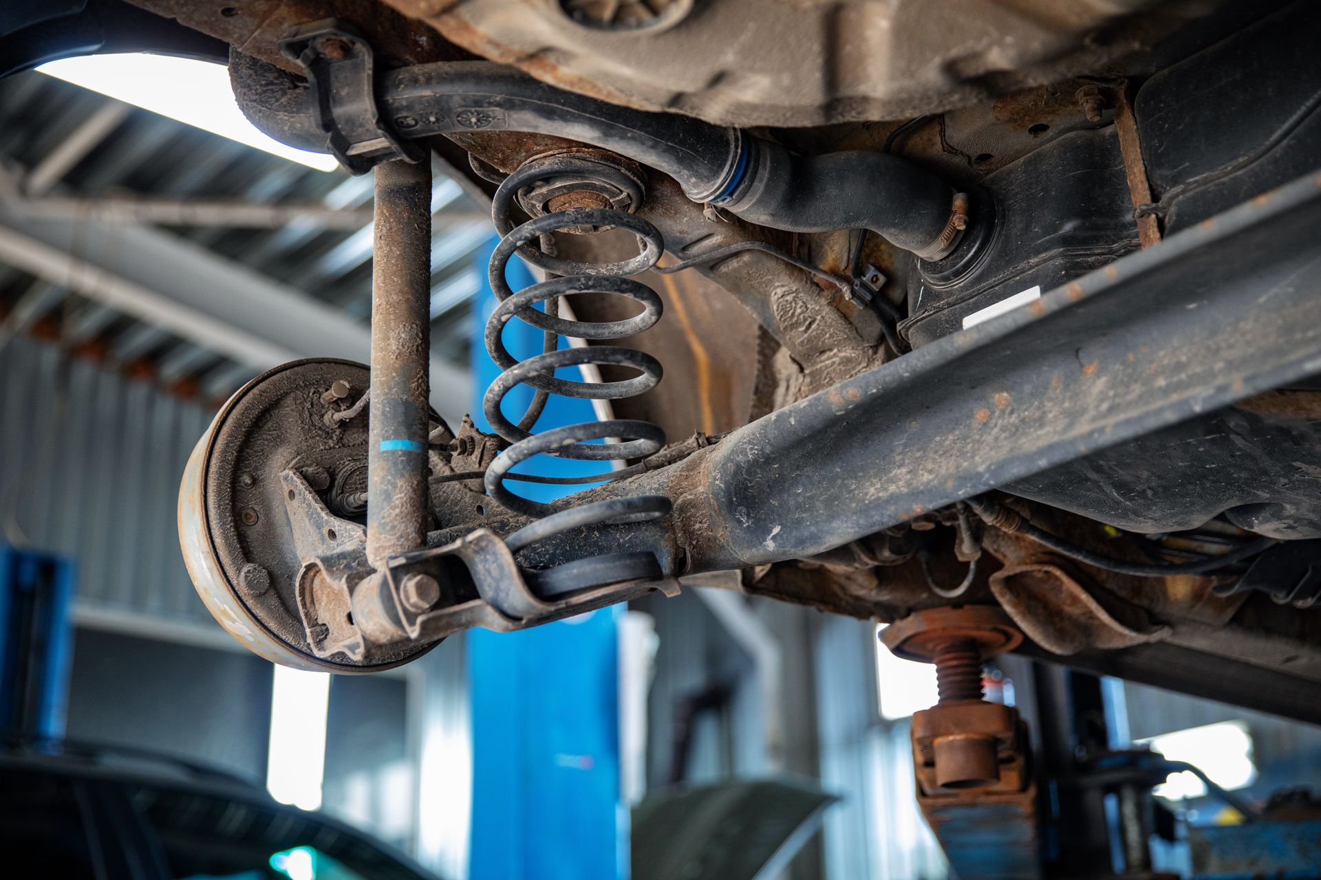 Close-up of an automotive vehicle's rear suspension system with a coil spring, shock absorber, and drum brake.