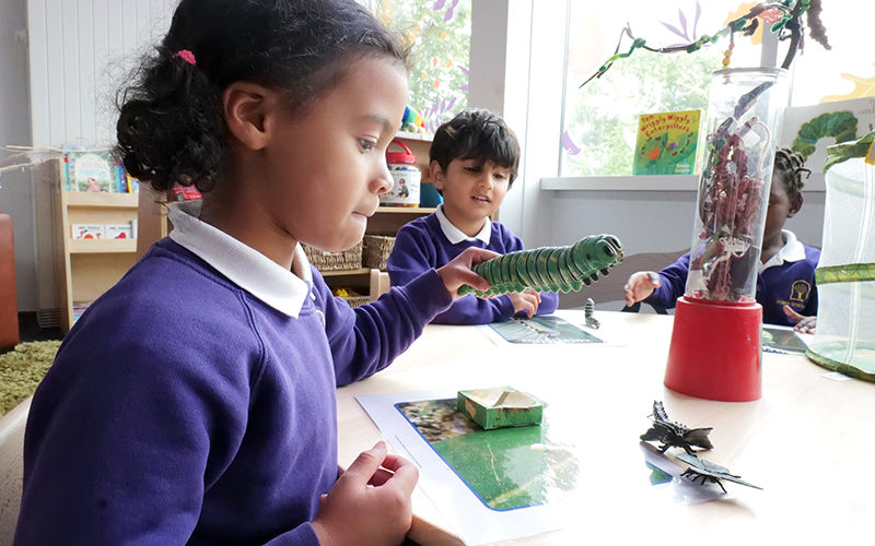 A girl in a purple sweater is sitting at a table playing with toys.