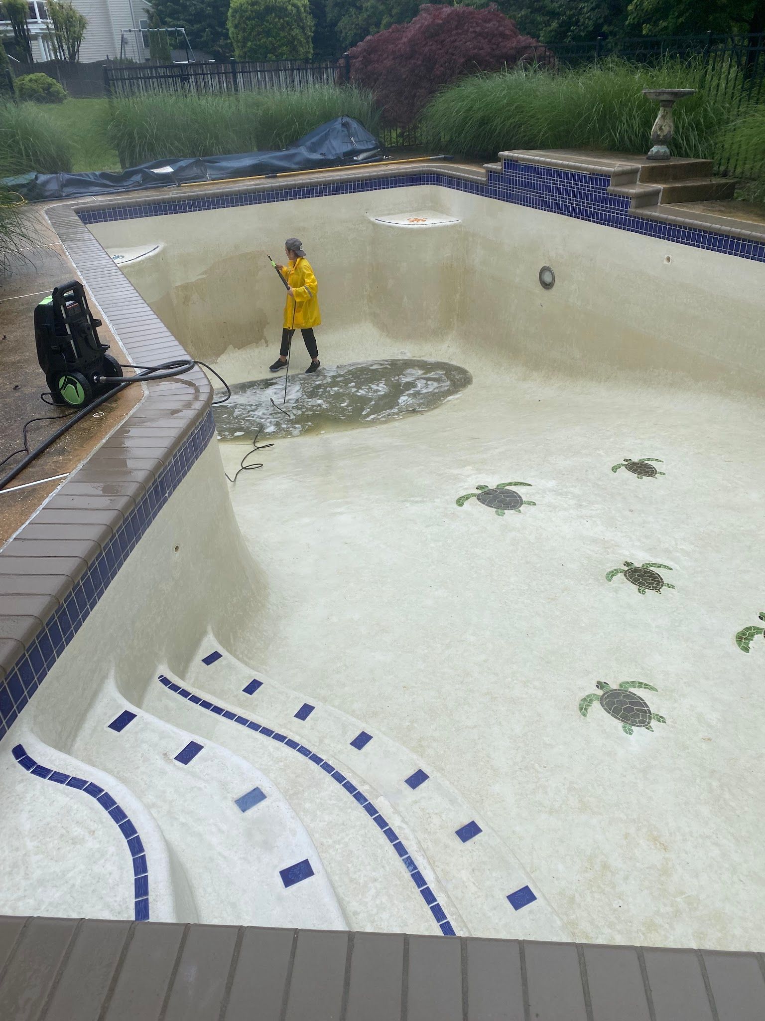 Empty drained swimming pool with a person in a yellow shirt standing near the shallow end