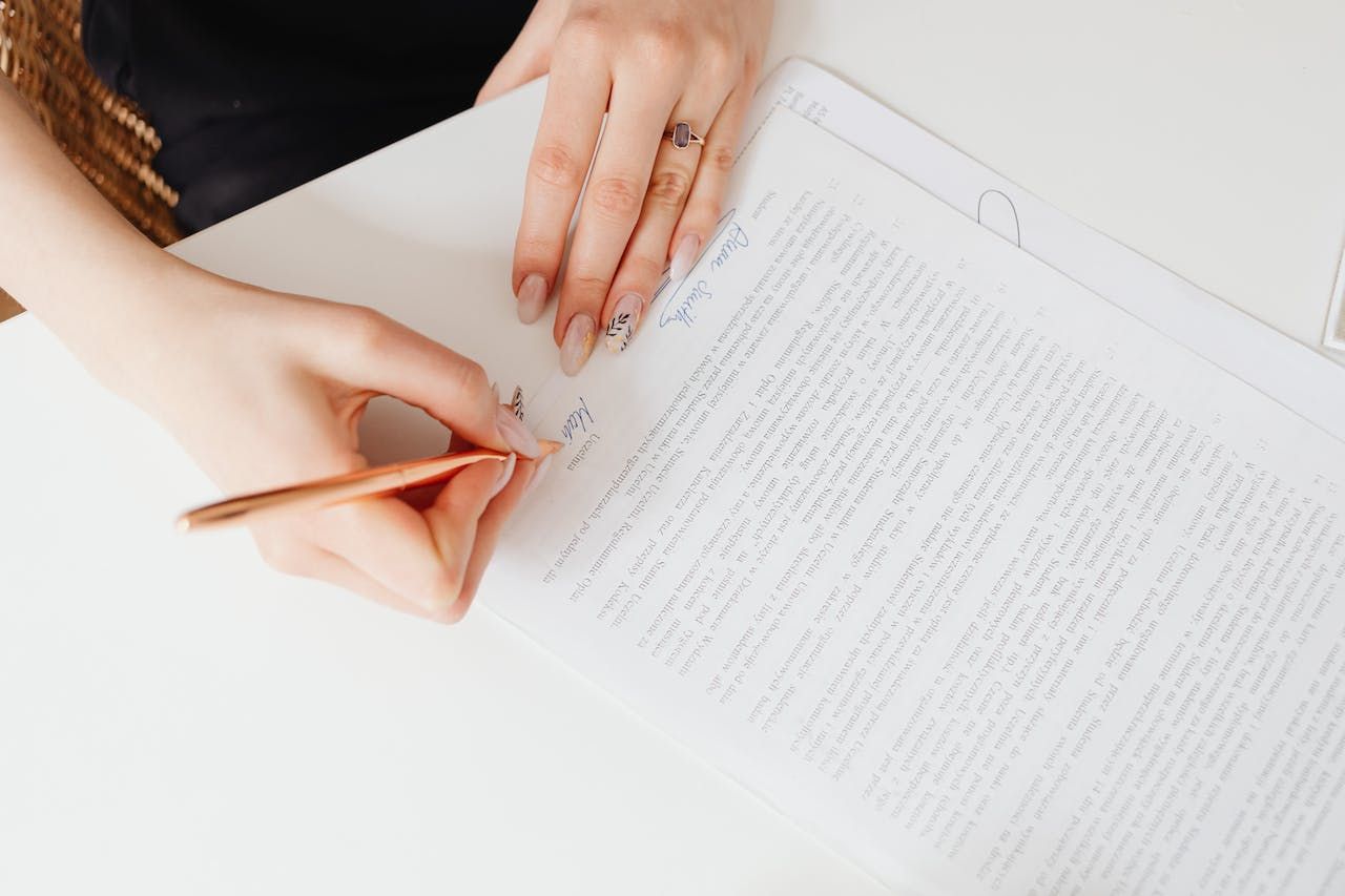 A woman is writing on a piece of paper with a pencil.