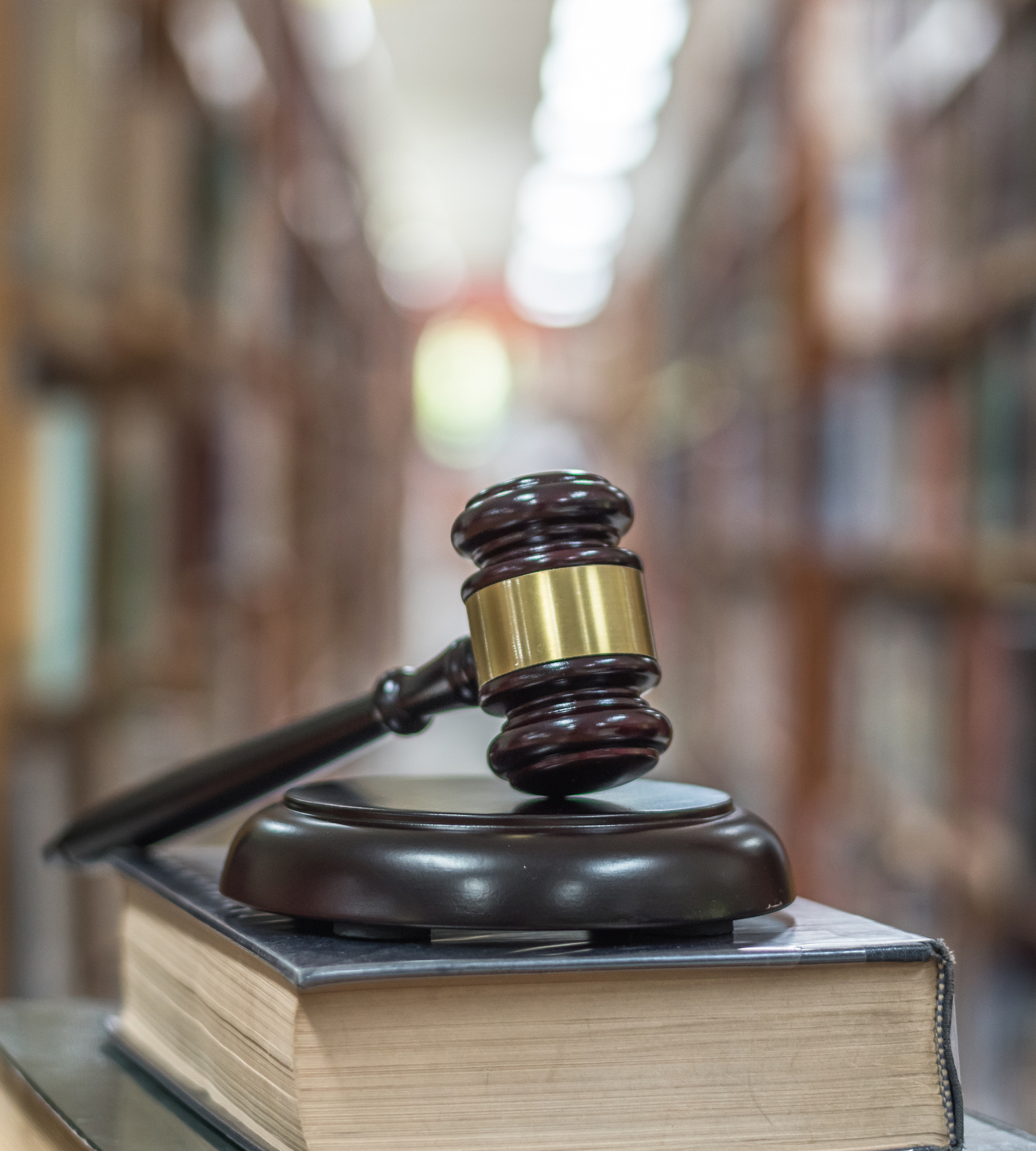 A judge 's gavel is sitting on top of a book in a library.
