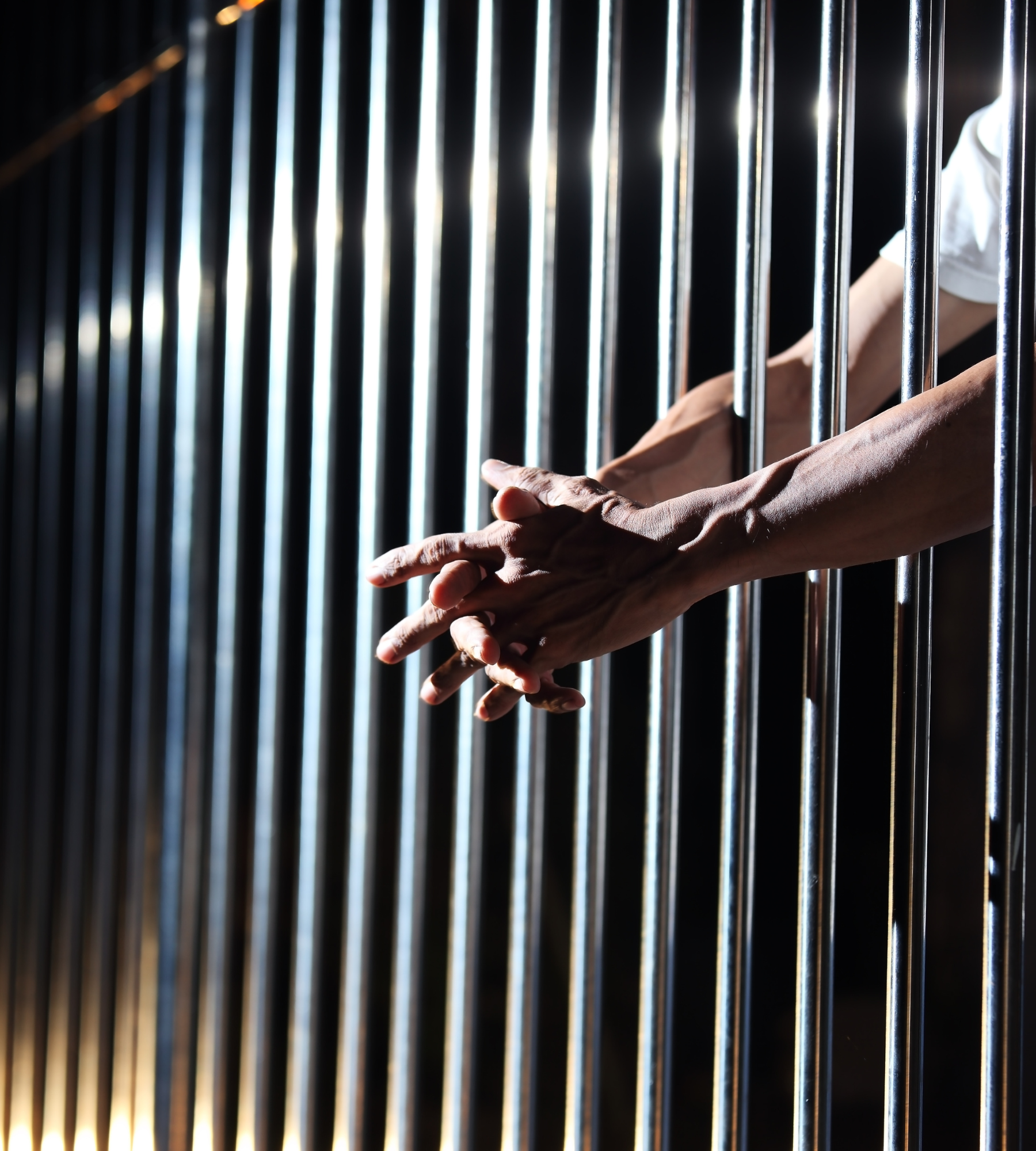 man in jail holding hands through bars