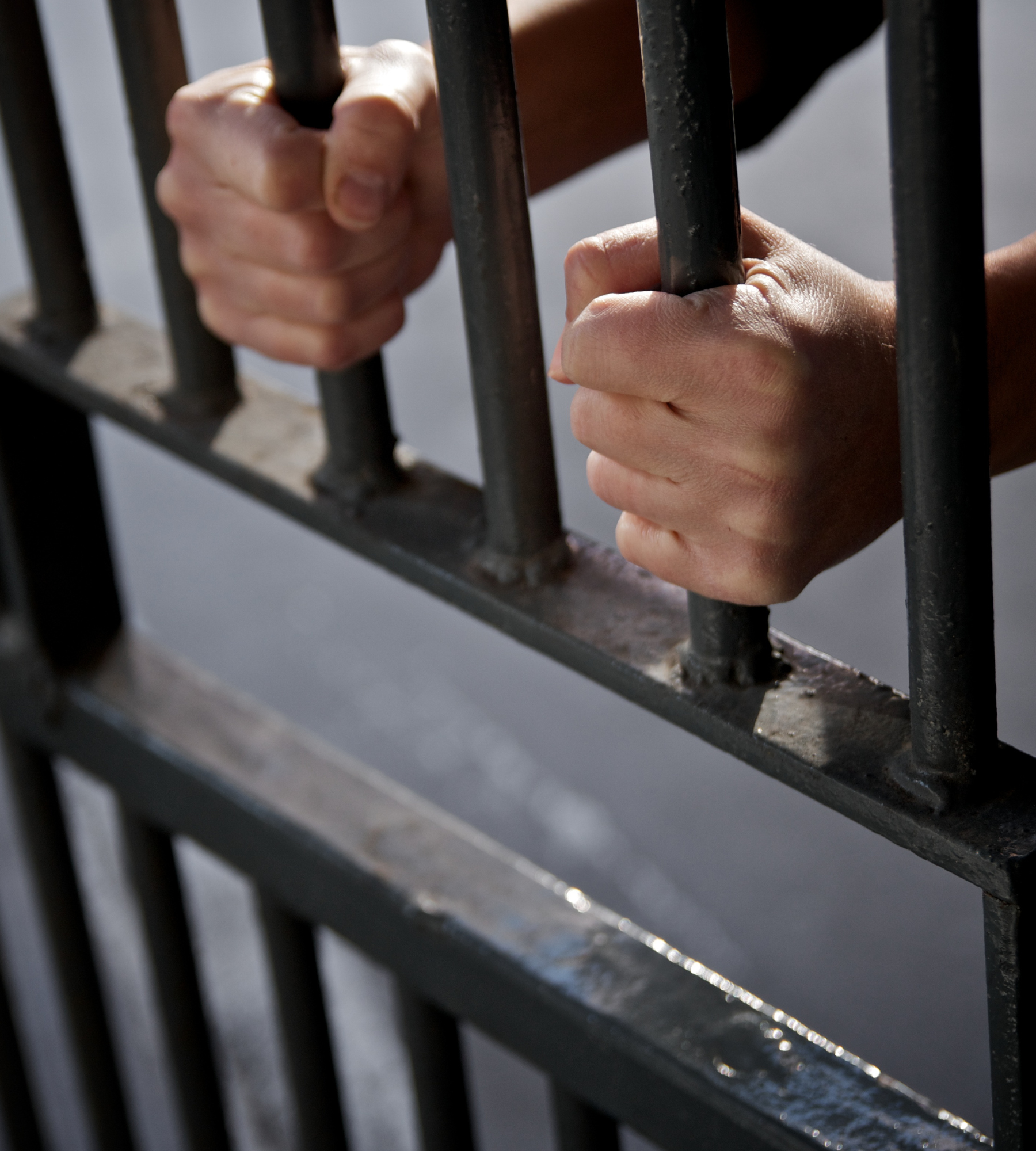 man in jail putting hands through bars