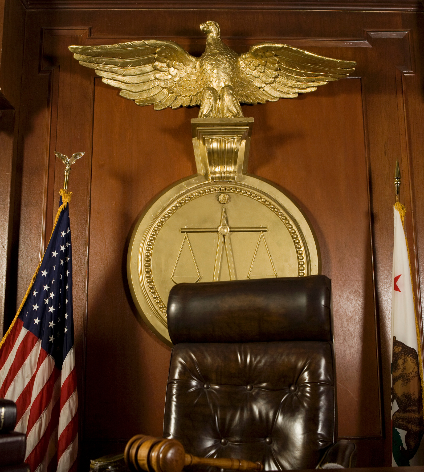 A judge 's chair with a gavel in front of a statue of an eagle