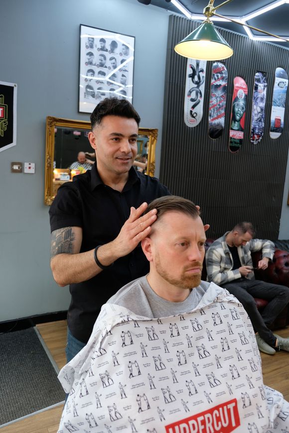 Matt is cutting a man 's hair in a barber shop