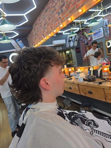 A young boy is getting his hair cut at a barber shop