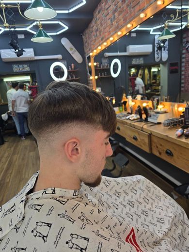 A young boy is giving a thumbs up in a barber shop