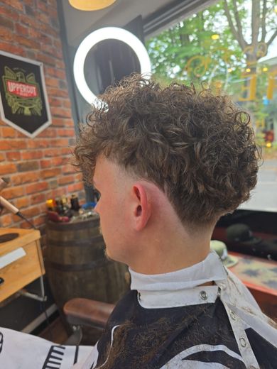 A young boy is getting his hair cut at a barber shop