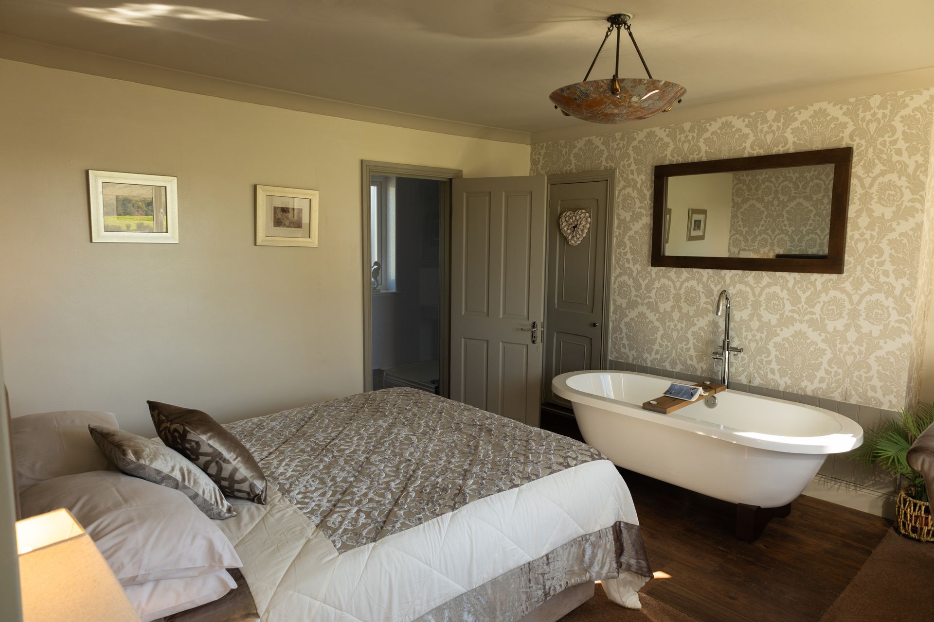 Cozy bedroom with a bed, clawfoot tub, wall mirror, and warm neutral decor