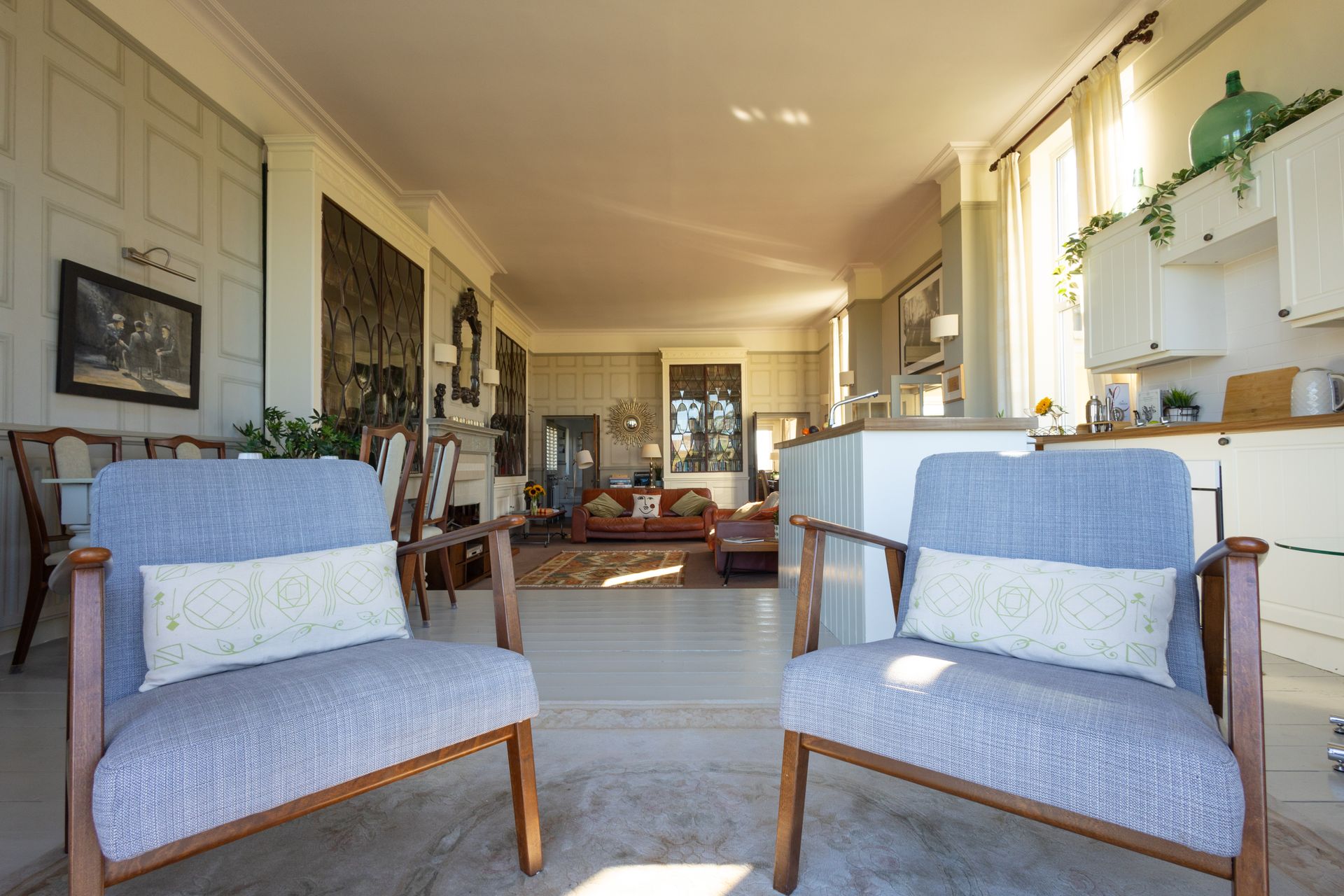 Bright living room with two blue chairs, windows, and a sunlit seating area