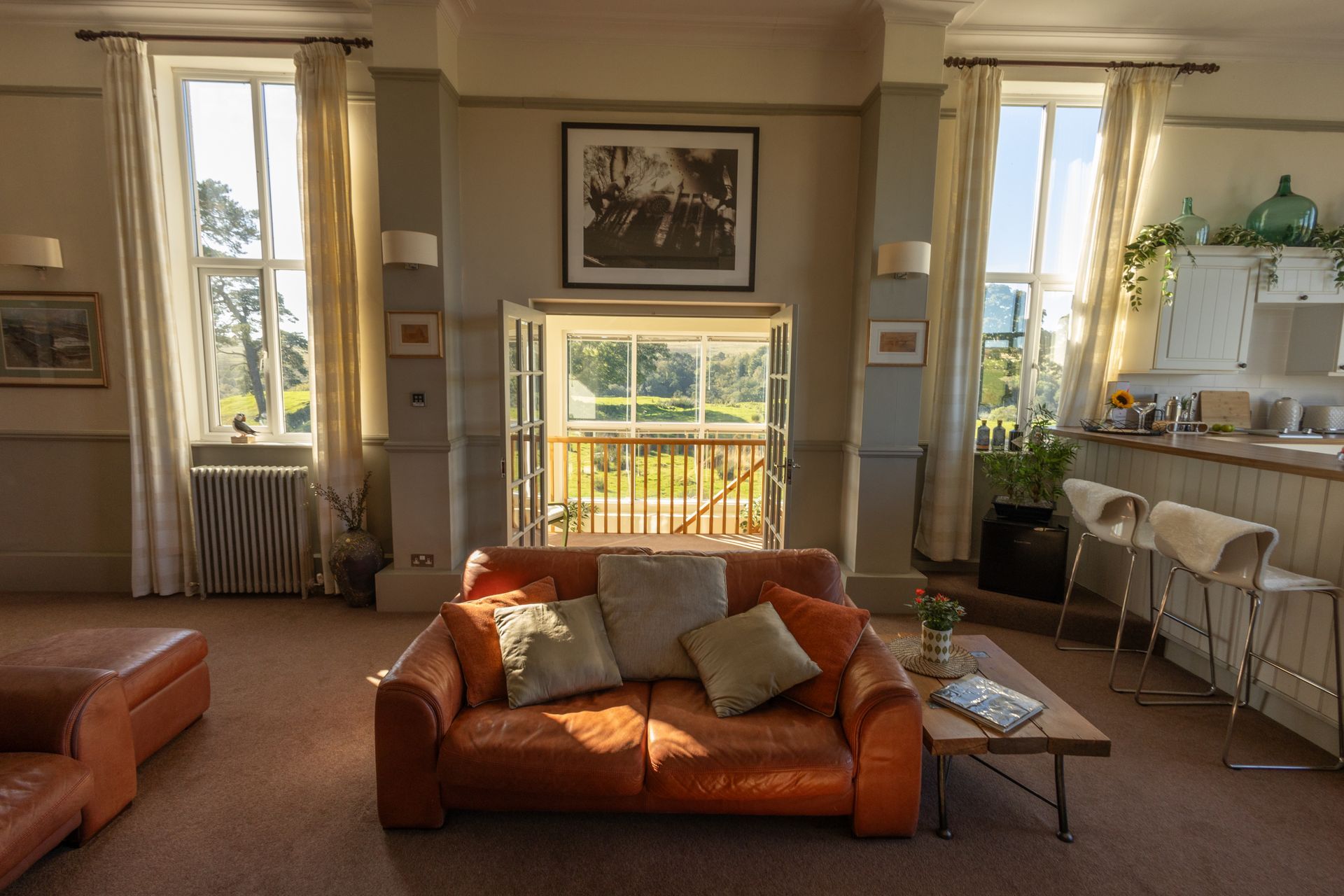 Sunny living room with orange sofas, large windows, and a balcony view
