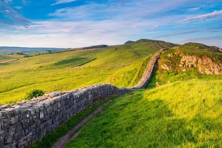 Stone wall winding along a green hillside under a bright sky