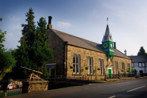 Stone church with green clock tower beside a road on a sunny day Bellingham