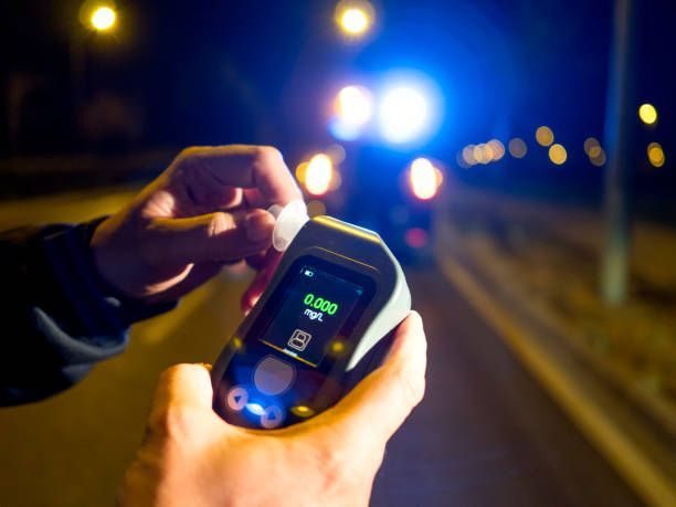 A person is holding a breathalyzer in their hand.