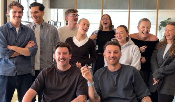 Group of smiling coworkers in a bright office, standing and sitting together for a team photo
