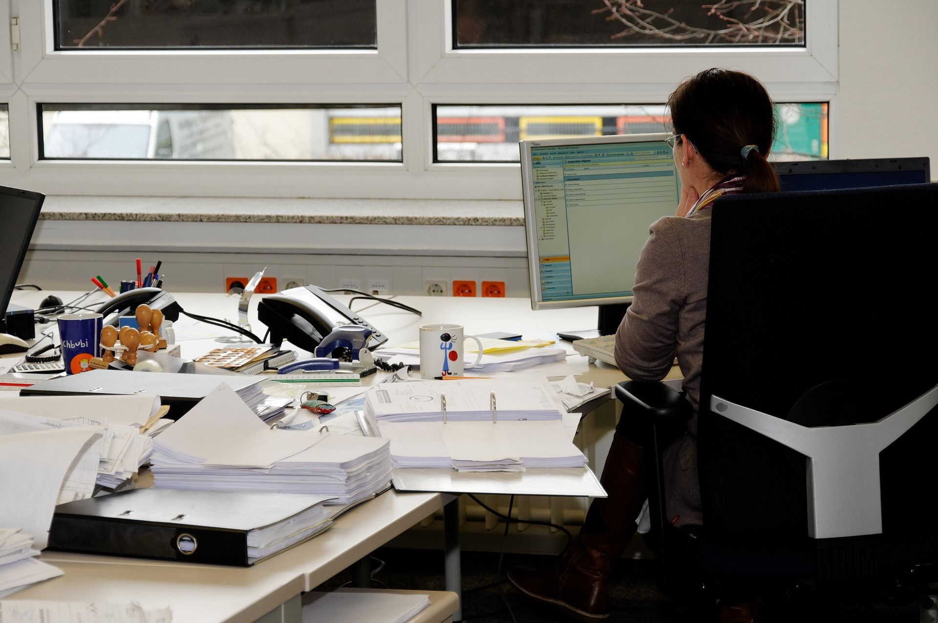 Woman smiling while using a desk phone in a busy office call center