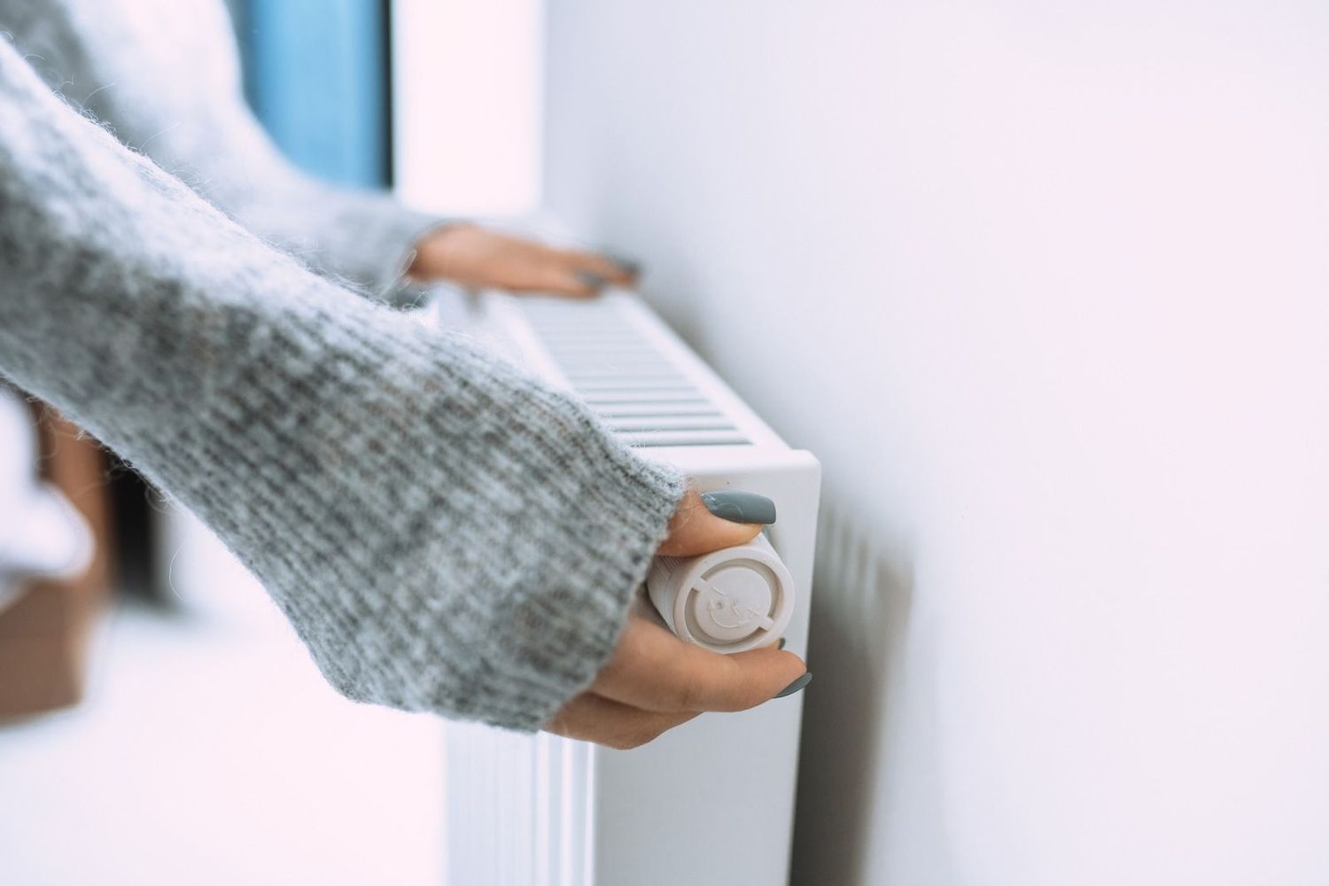 A person is adjusting the temperature of a heater.