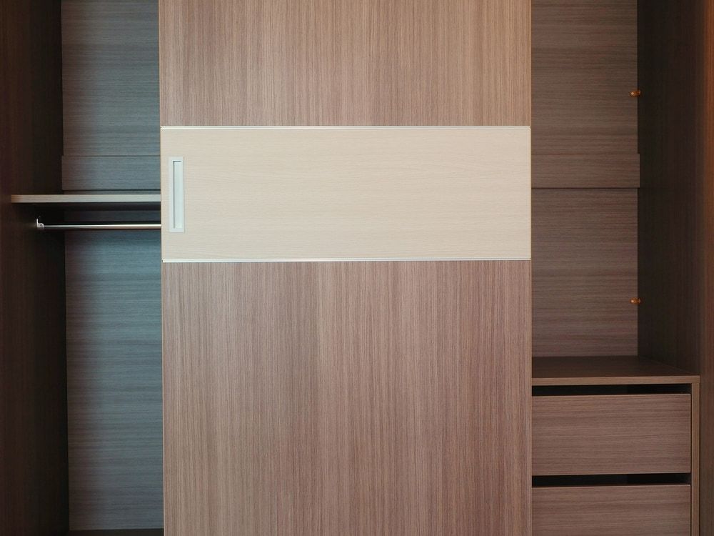 A Wooden Cabinet With Sliding Doors And Shelves In An Empty Room — Browny's Glass & Aluminium in Wingham, NSW