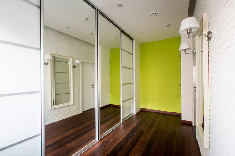 A hallway with sliding mirrored doors and a green wall. — Browny's Glass & Aluminium in Wingham, NSW
