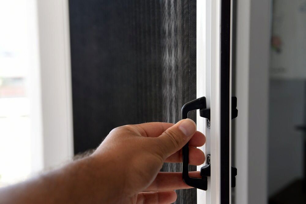 A Person Is Opening A Door With A Black Handle — Browny's Glass & Aluminium in Wingham, NSW