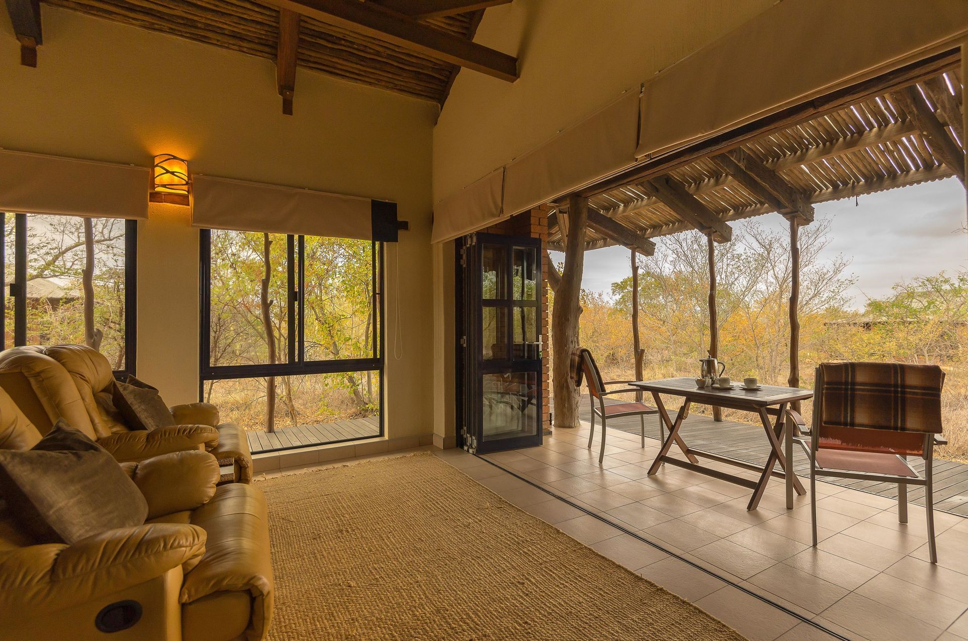 Open-air living room with wicker chairs, thatched ceiling, and outdoor view through wide windows