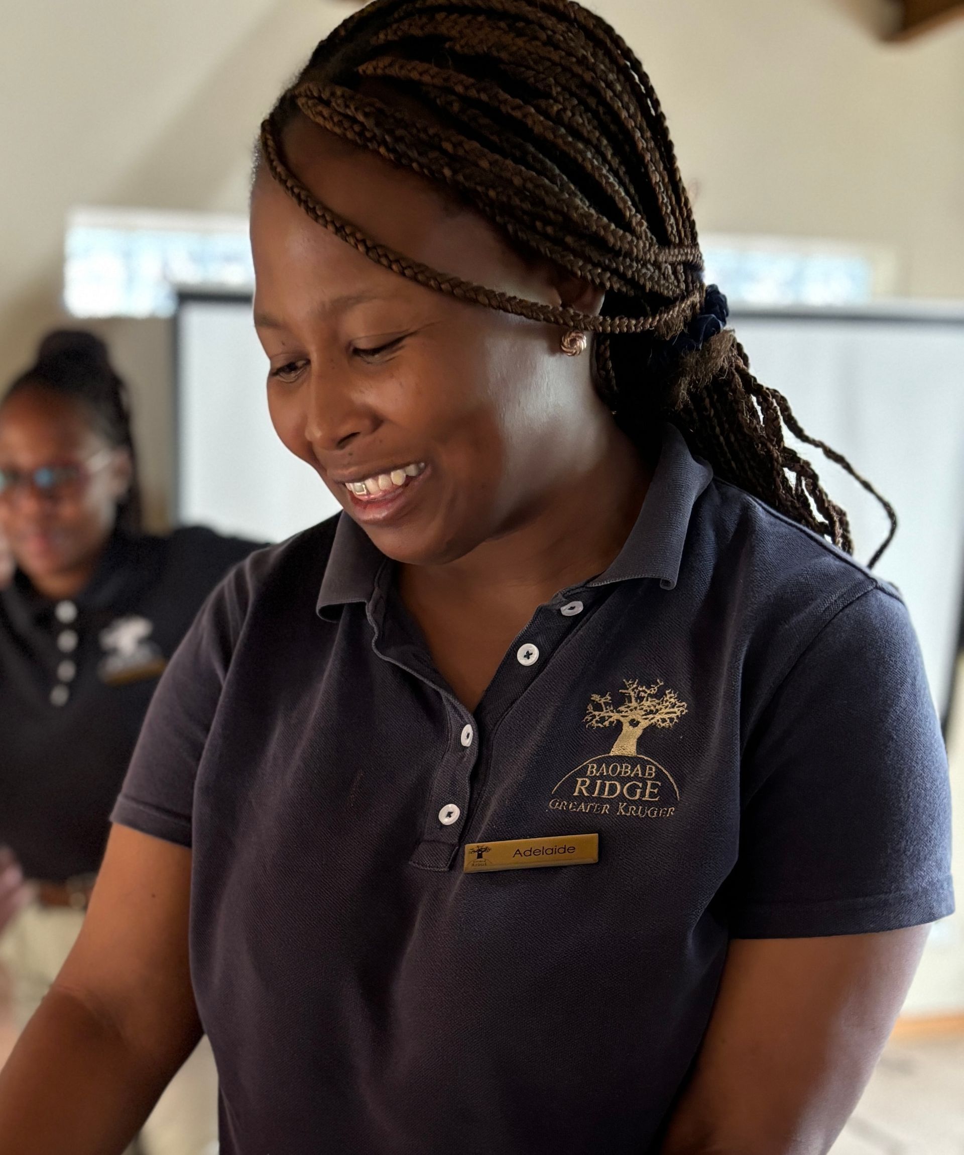 Smiling woman in a navy polo shirt writing in a classroom or workshop setting
