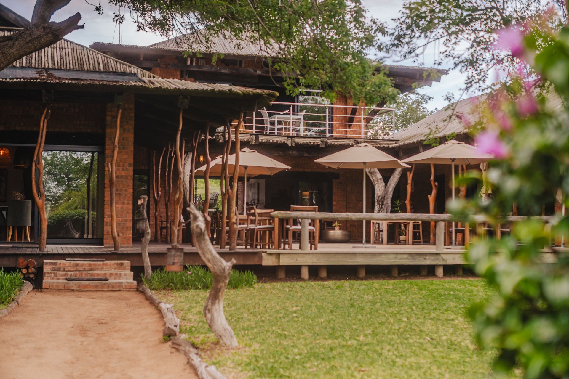 Rustic wooden lodge with porch and patio seating, surrounded by a green lawn and trees