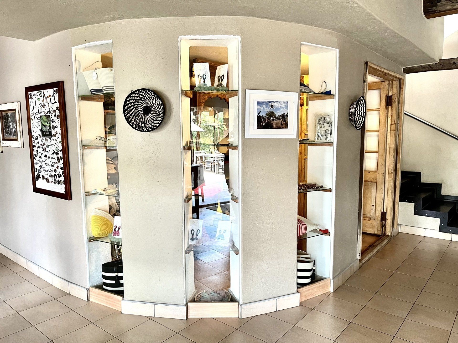 Curved hallway with recessed display shelves, wall art, and tiled floor in a bright home interior