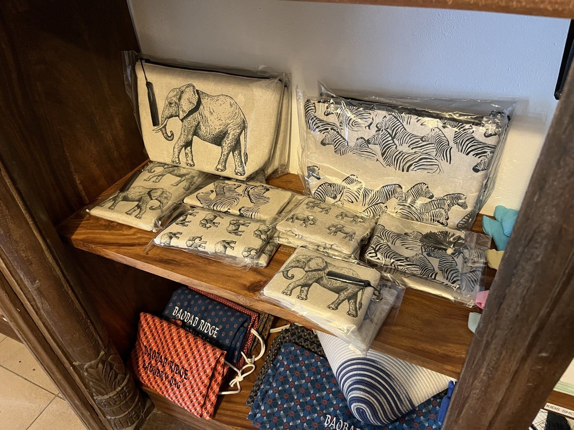 Displayed cushion covers and fabric samples on a wooden shelf in a store.