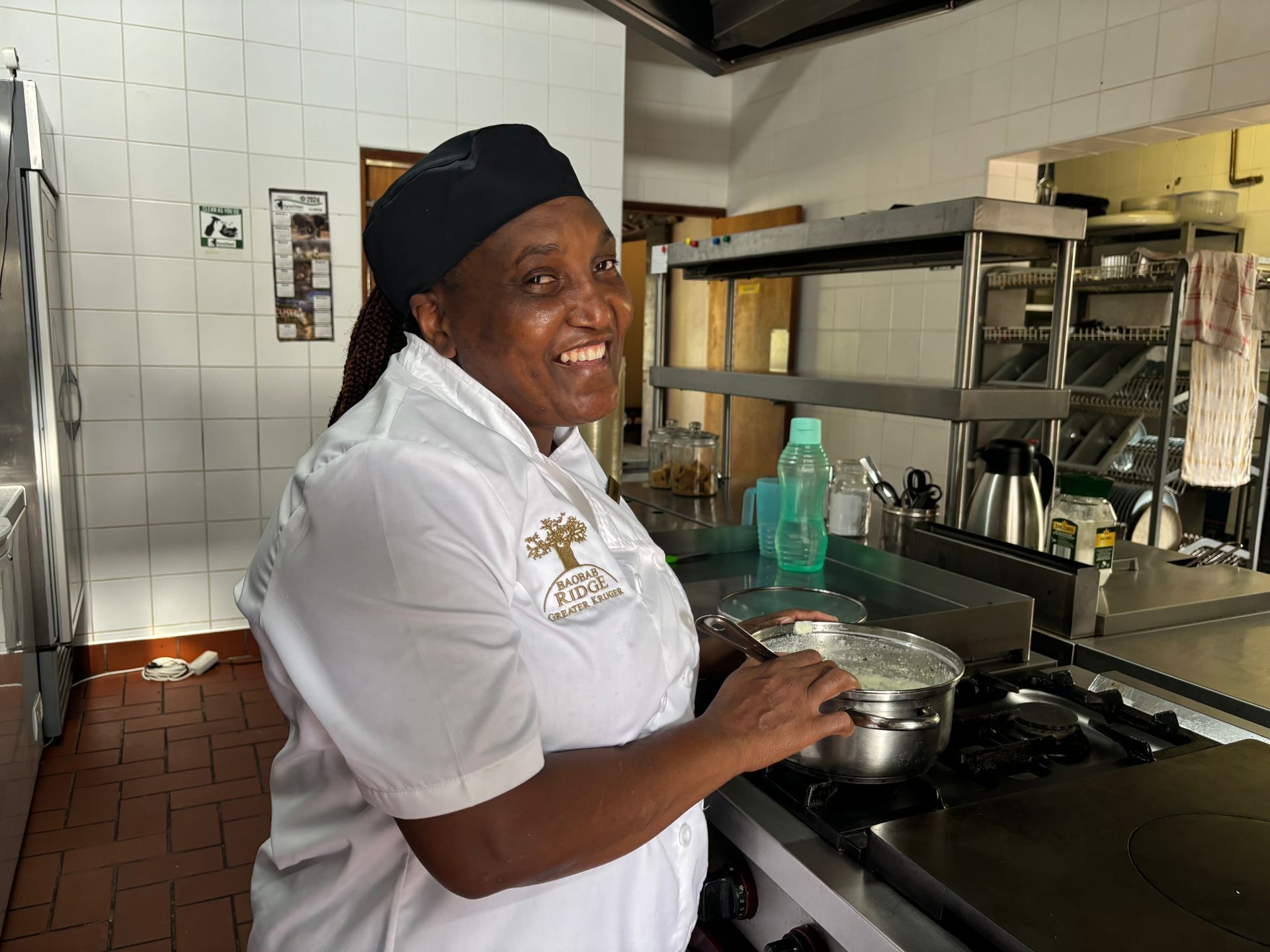 Chef smiling in a commercial kitchen while cooking at the stove