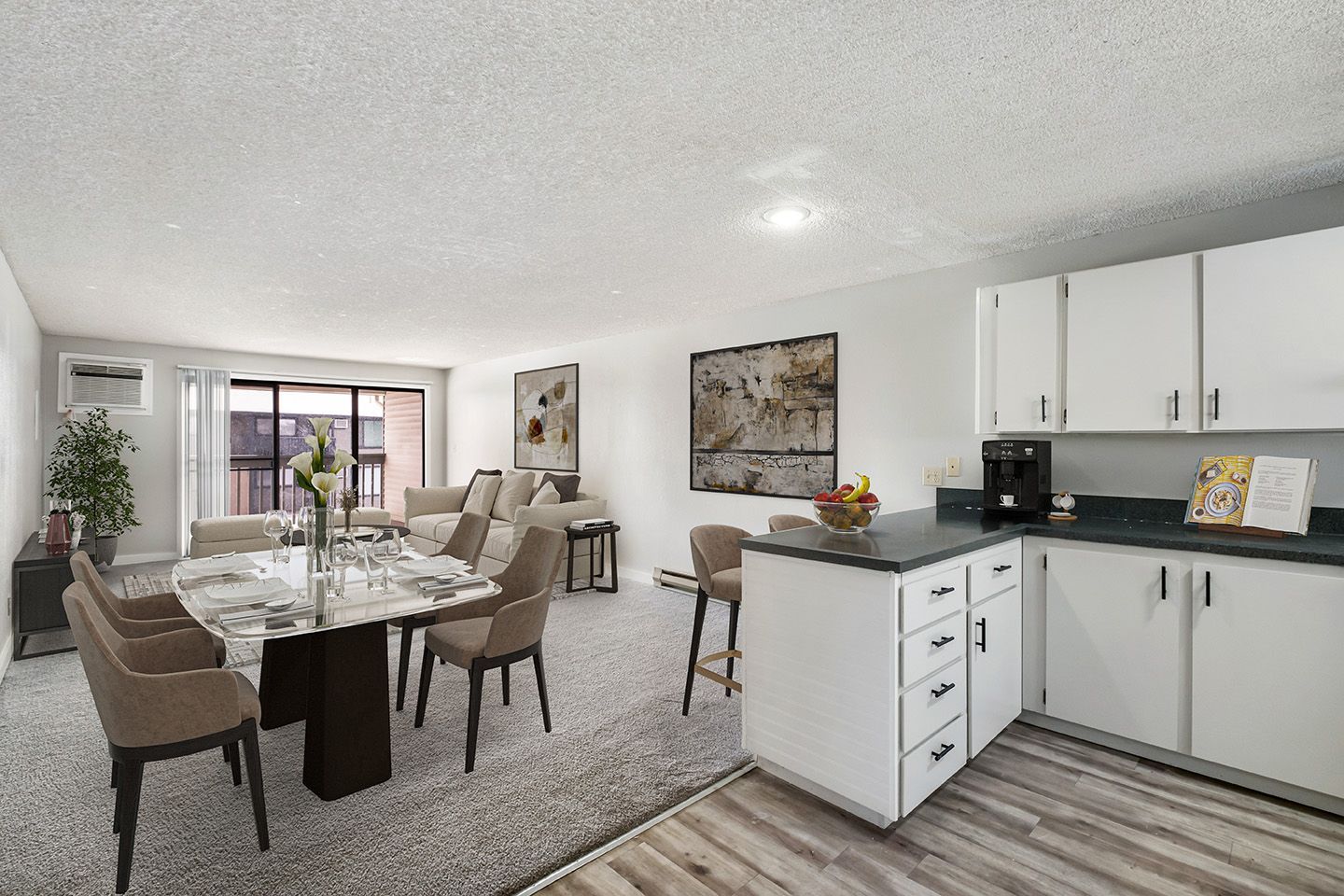 Modern dining and kitchen area with gray chairs, white cabinets, and carpeted living space