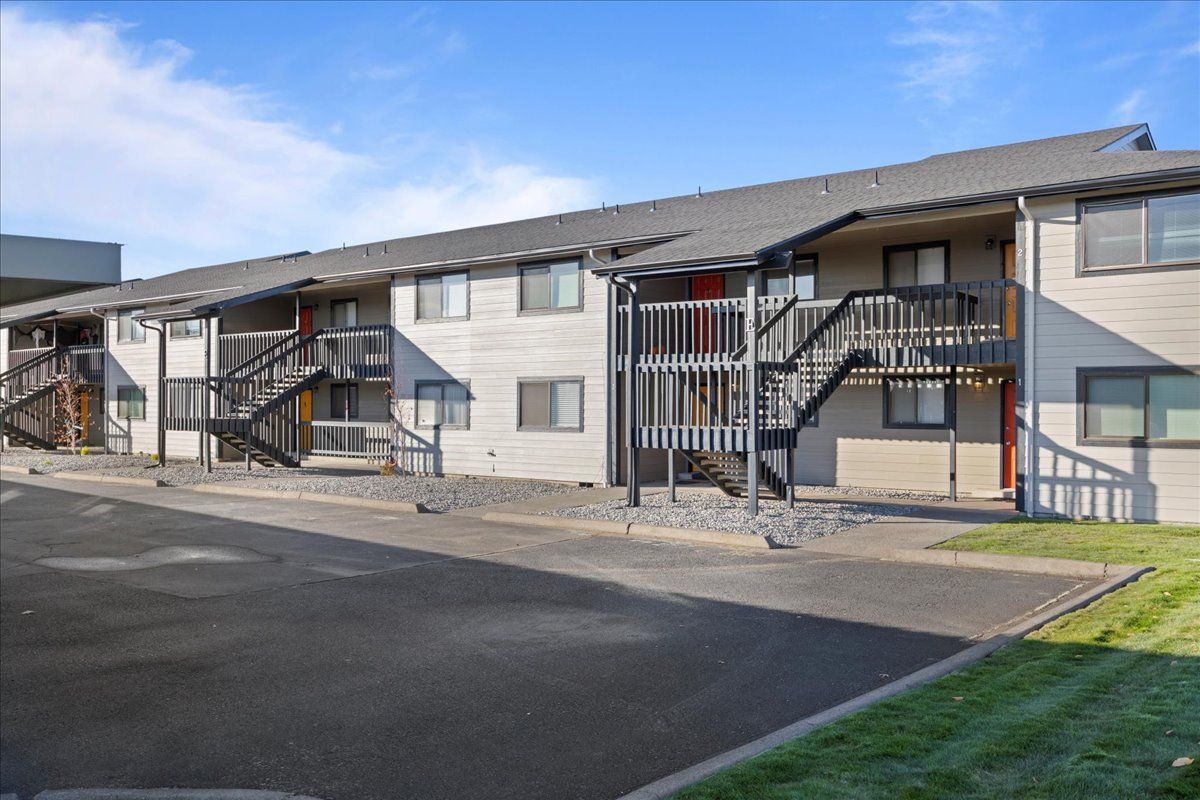 Exterior of an apartment building with covered stairways and a paved parking area