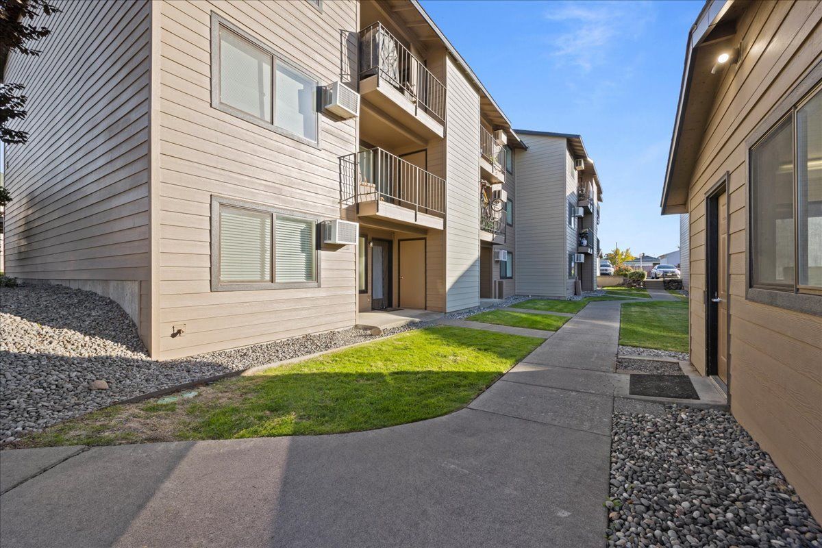 Apartment buildings with a sidewalk and green lawn in a sunny courtyard