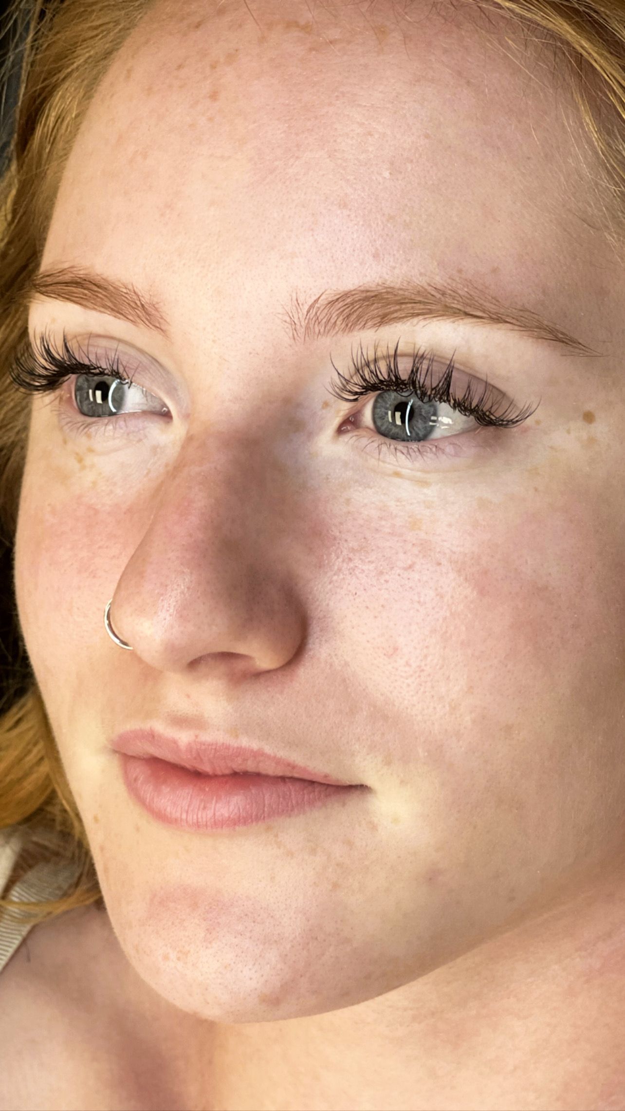 A close up of a woman 's face with a nose ring.