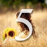 A woman is sitting in a field of tall grass next to a sunflower.