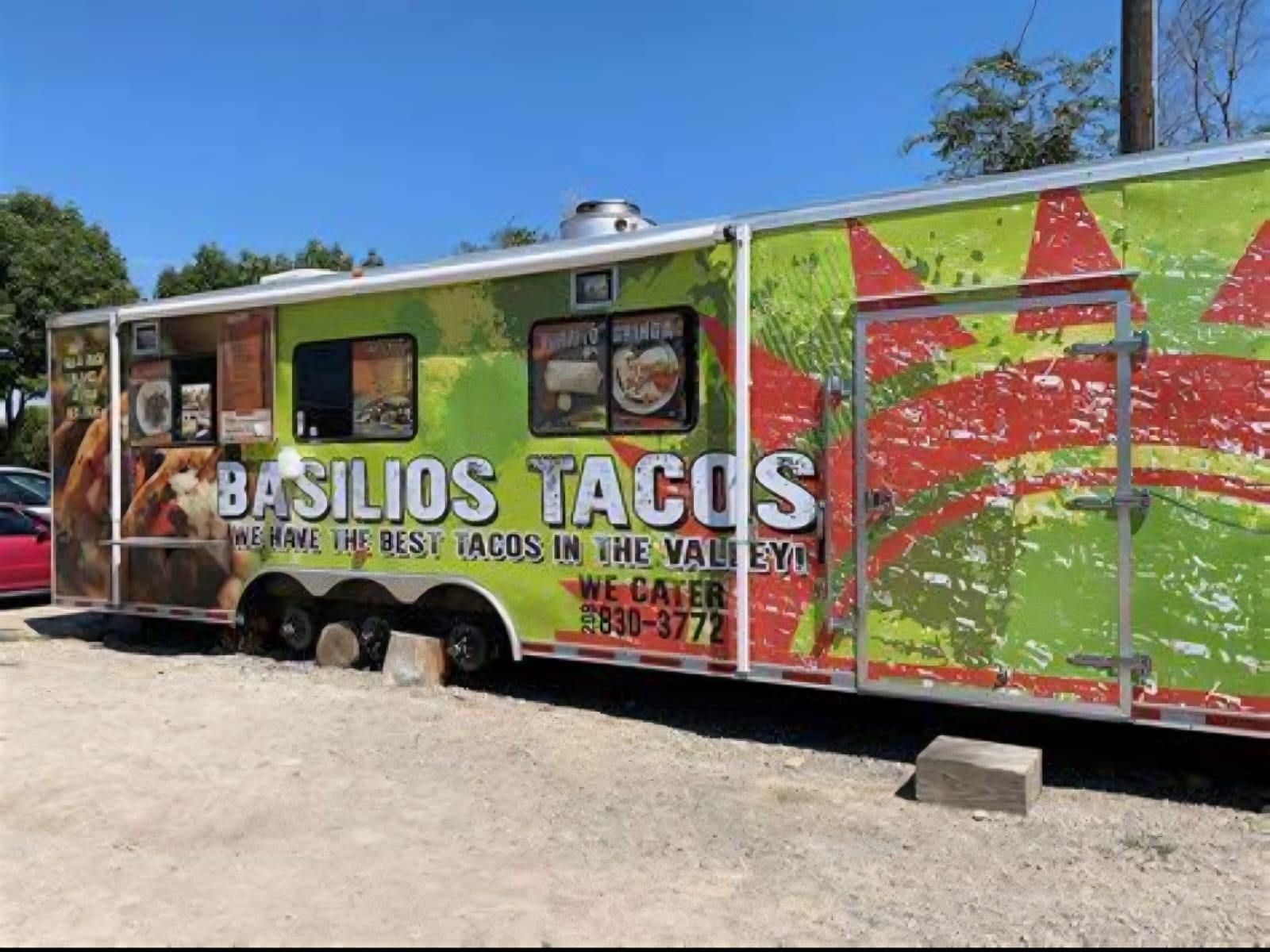 Taco food truck at a gas station with tacos pictured on the side. A car is parked in front.