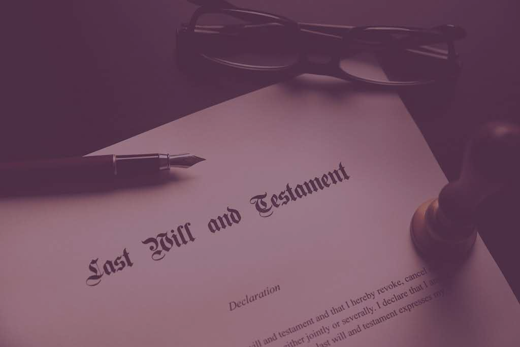 A close up of a last will and testament with a pen and glasses.