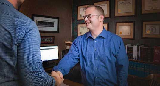 Two men are shaking hands in an office.