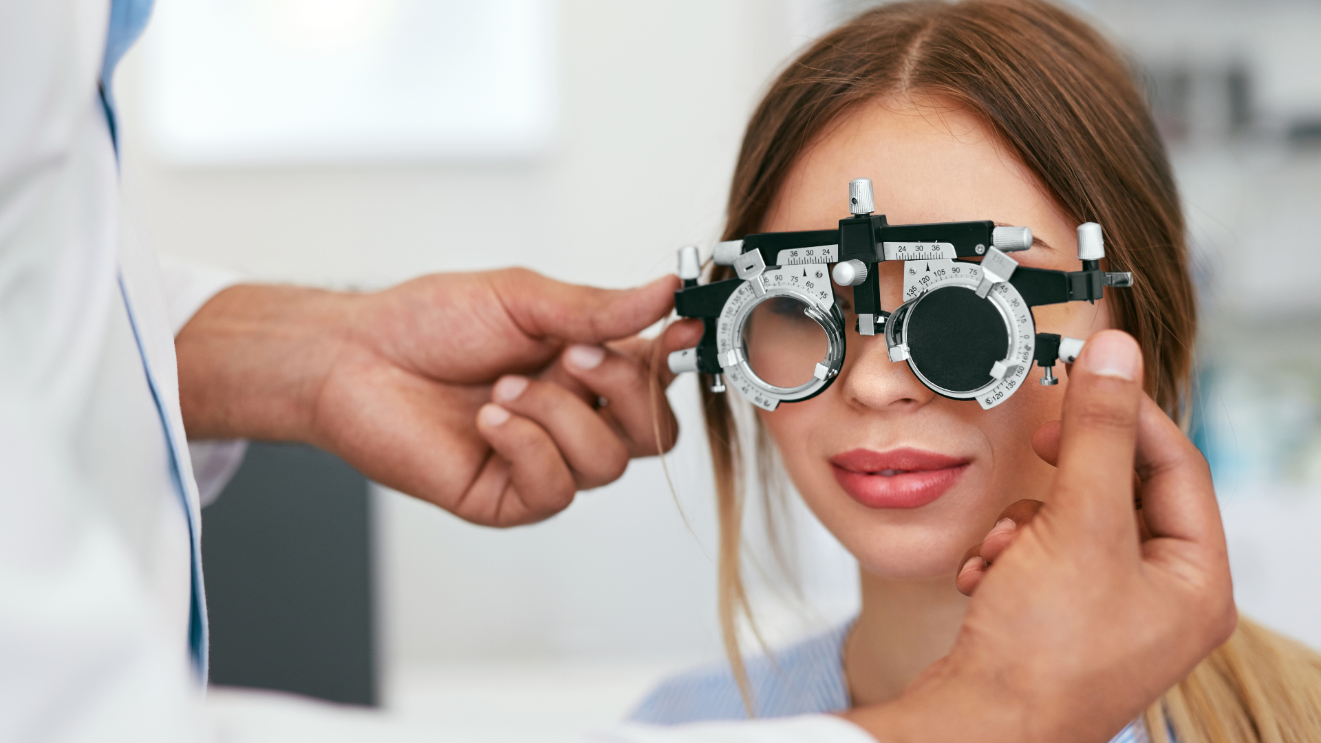 Optometrist adjusting a phoropter on a woman during an eye exam.