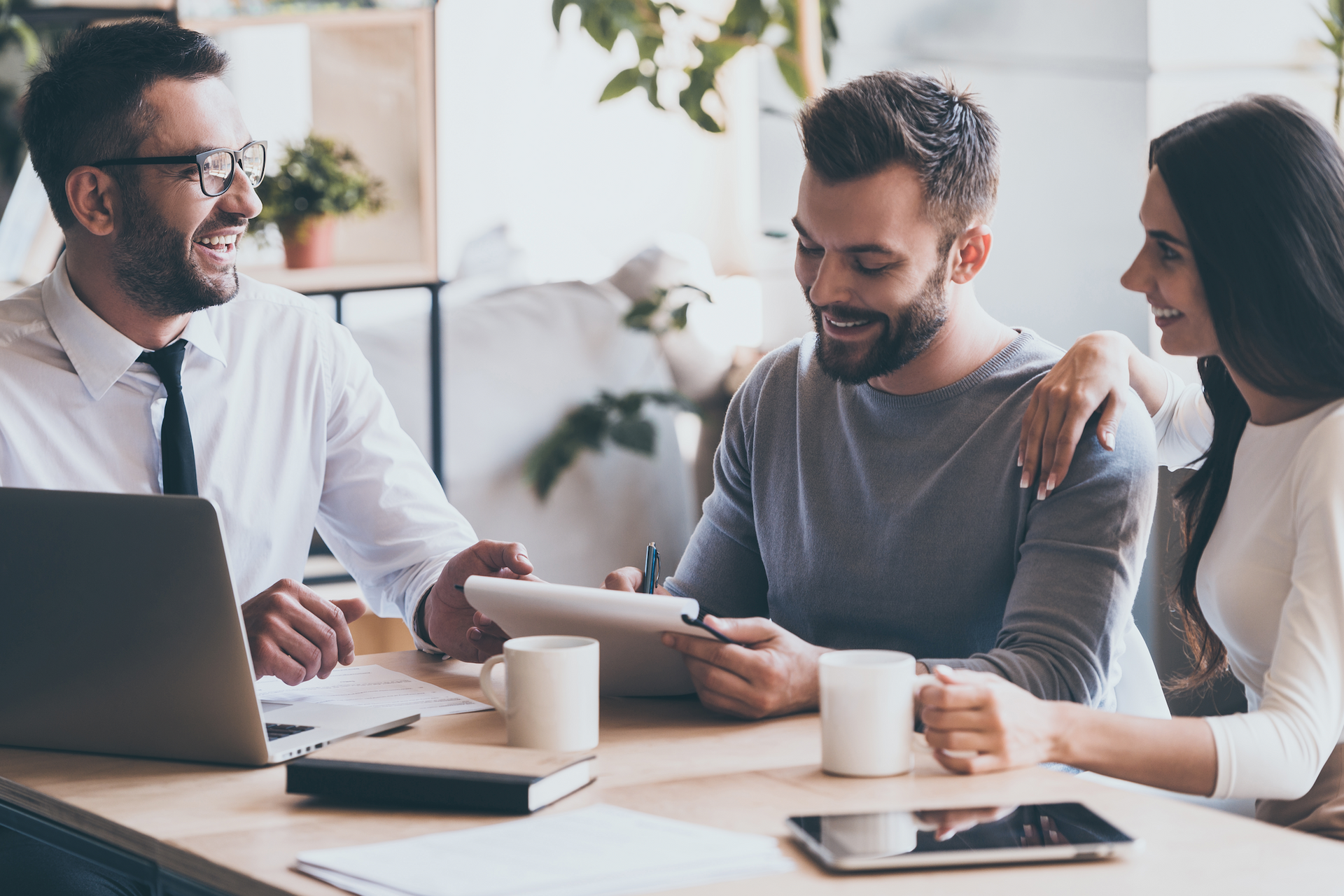 A man and a woman are sitting at a table with a laptop and a tablet.
