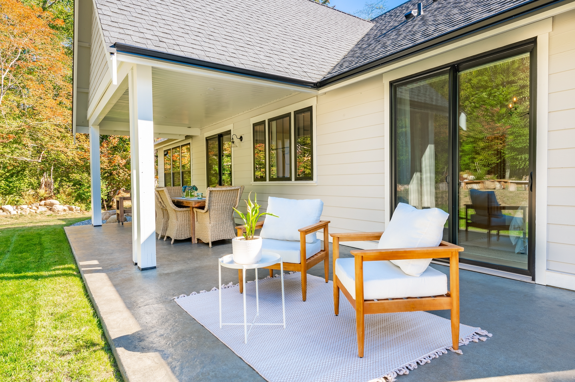 There are two chairs and a table on the patio of a house.