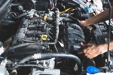 Mechanic working on a car engine with tools in an auto repair shop
