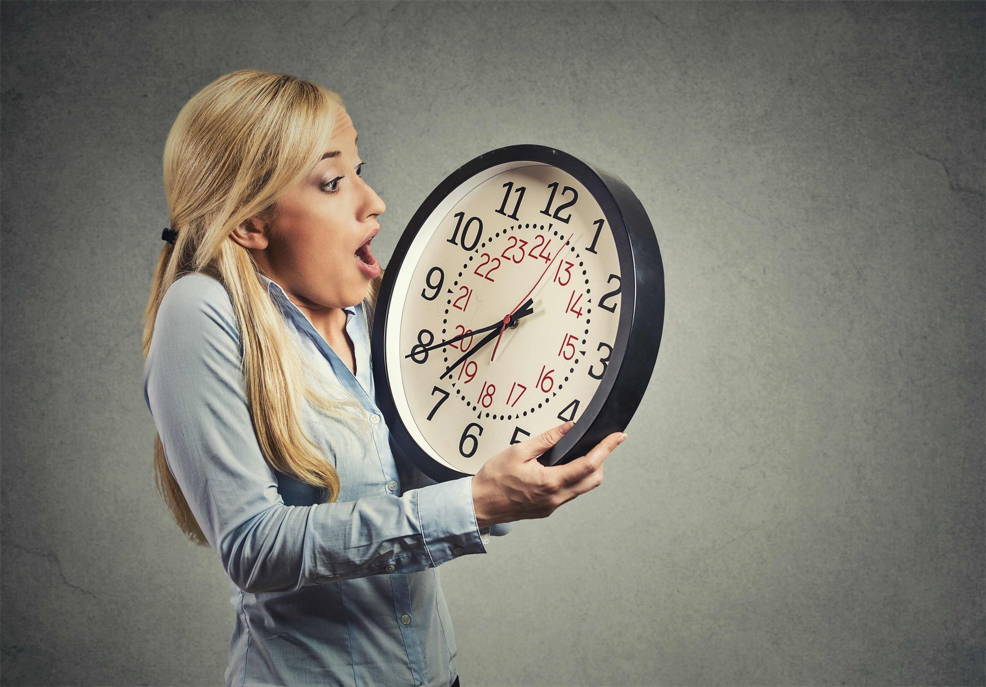 A woman holding a big clock to symbolize a large remodeling project