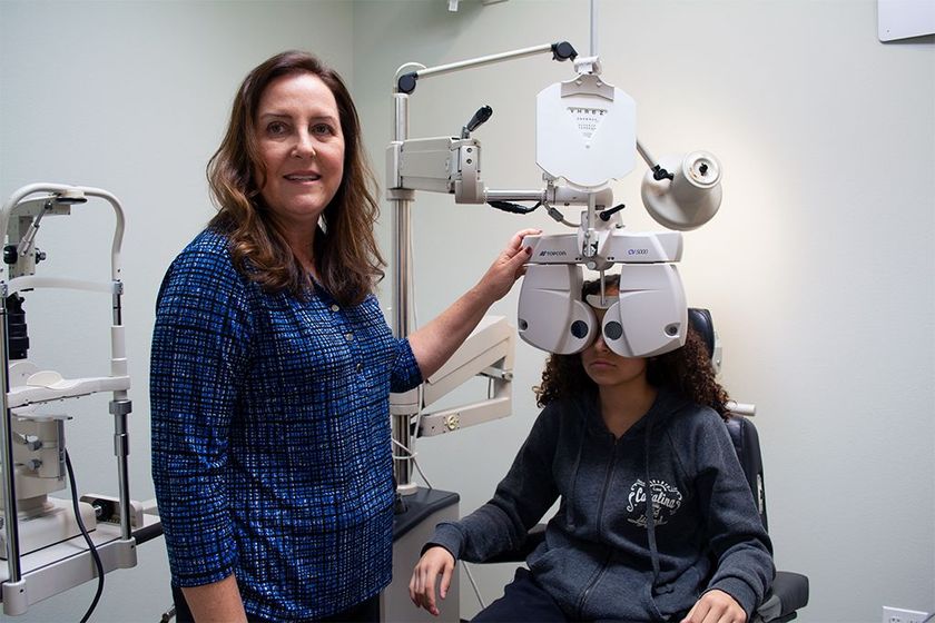 Optometrist performing a vision test on a young teenage girl